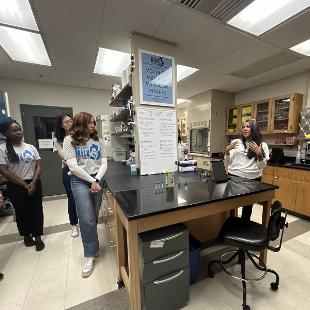 Photo of faculty member talking with students in lab setting. 