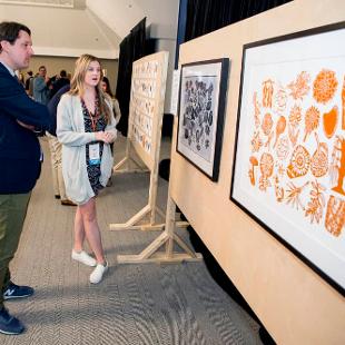 A Hope Forward student talks to Nate Haveman while looking at a framed artwork