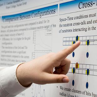 A student points to a close-up of a research poster