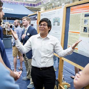 A male student presenting his research on a poster