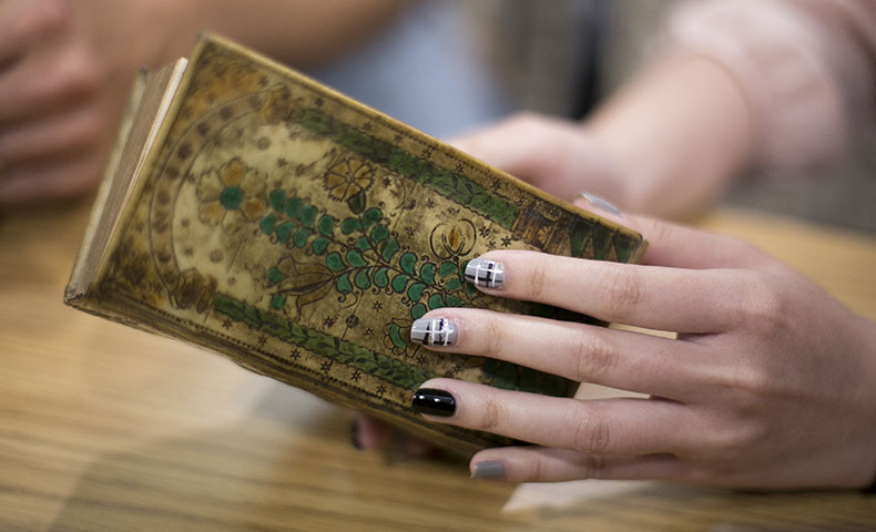 Manicured fingernails on a rare book